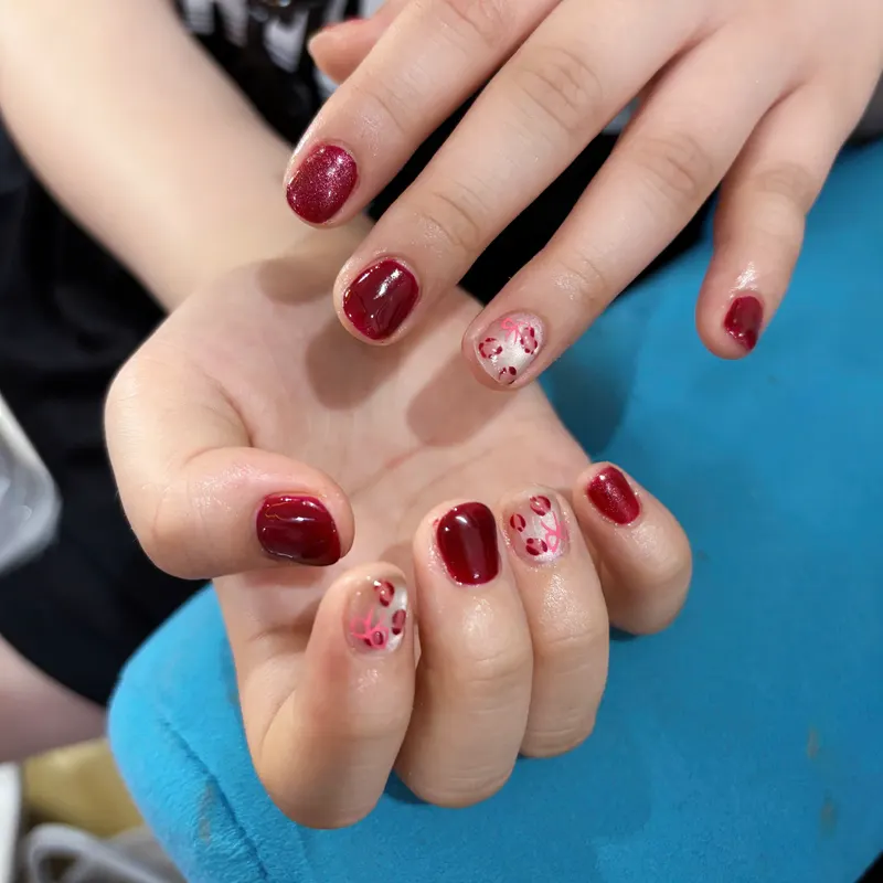 Dark red nails with delicate floral art by LENA Nails & Beauty, nail salon in Da Nang