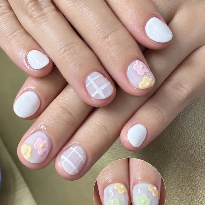 White nails with 3D pastel flowers and plaid art by LENA Nails & Beauty, nail salon in Da Nang