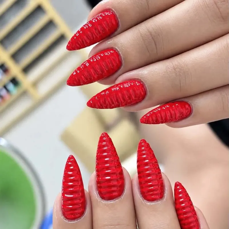 Red stiletto nails with 3D textured art by LENA Nails & Beauty, nail salon in Da Nang