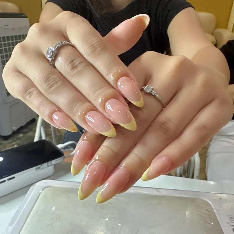 Nude almond nails with yellow French tips by LENA Nails & Beauty, nail salon in Da Nang