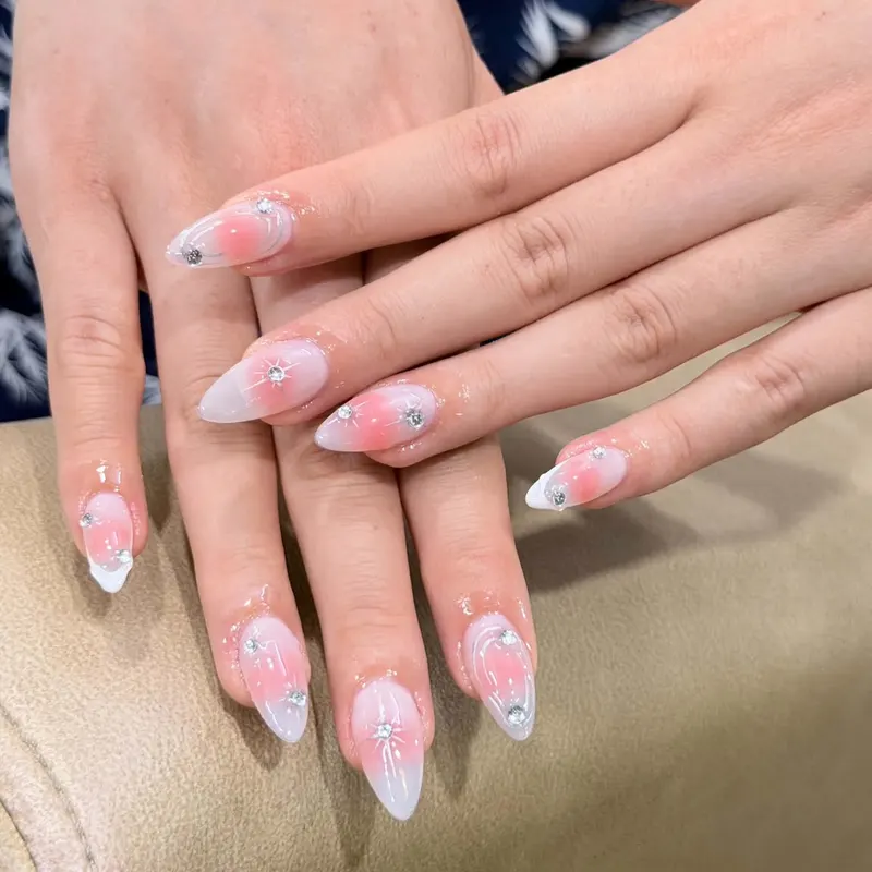 Pink almond nails with white flowers and rhinestones by LENA Nails & Beauty, nail salon in Da Nang
