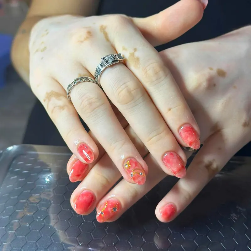 Red nails with gold floral art by LENA Nails & Beauty, nail salon in Da Nang