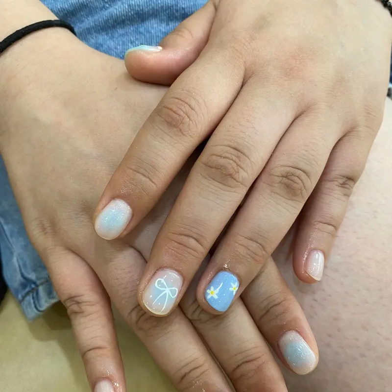 Pale blue nails with white bow and flower art by LENA Nails & Beauty, nail salon in Da Nang