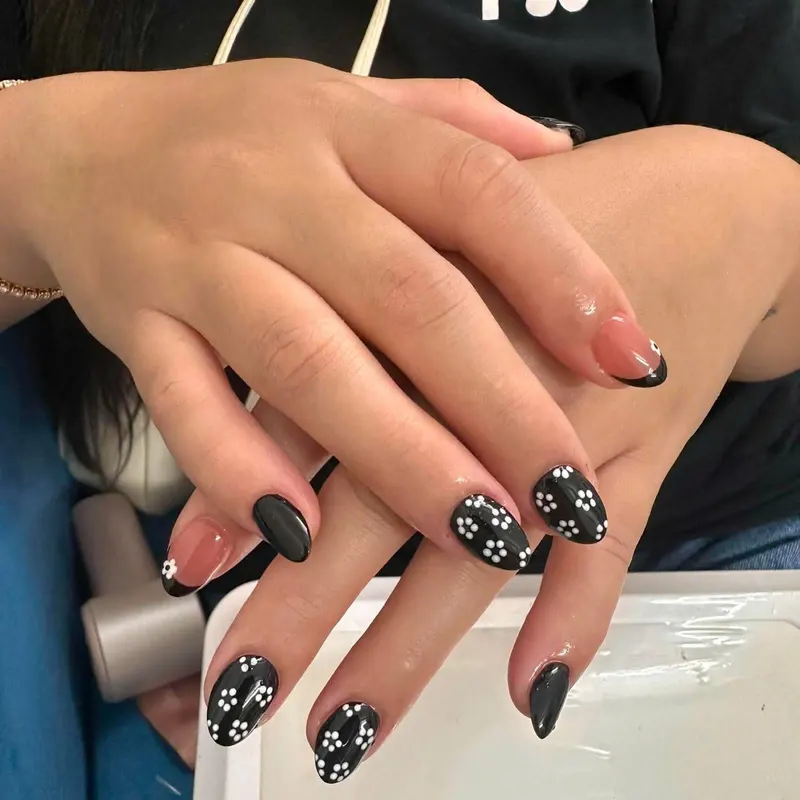 Black nails with white daisy art by LENA Nails & Beauty, nail salon in Da Nang