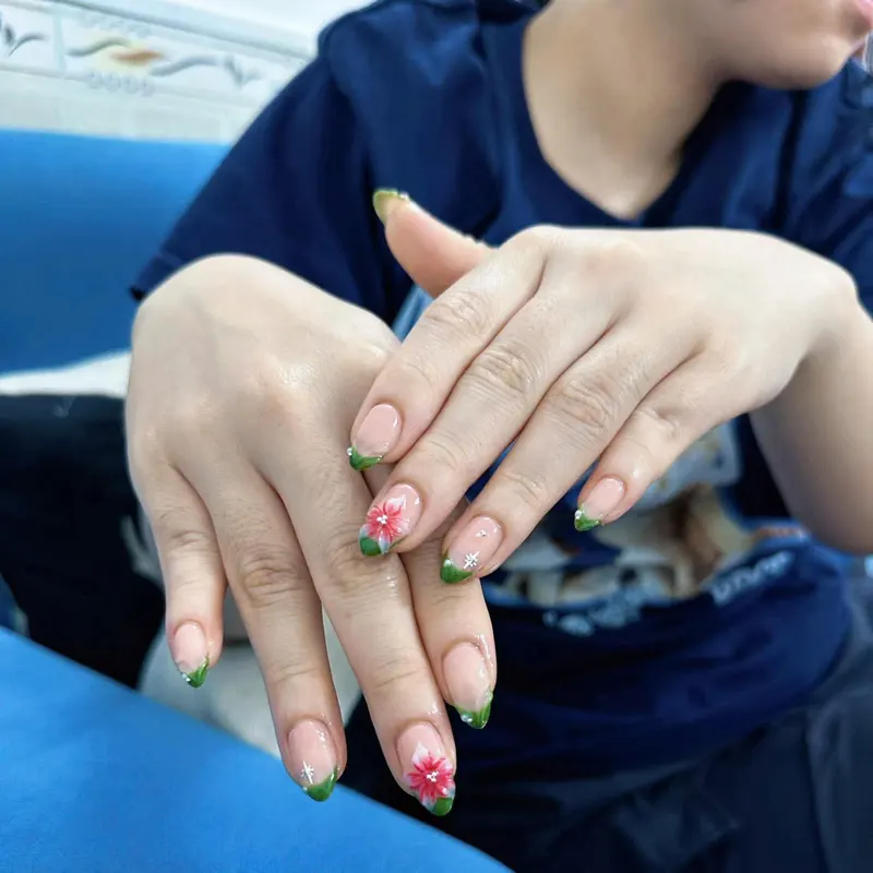 Green French tips with pink flower art by LENA Nails & Beauty, nail salon in Da Nang